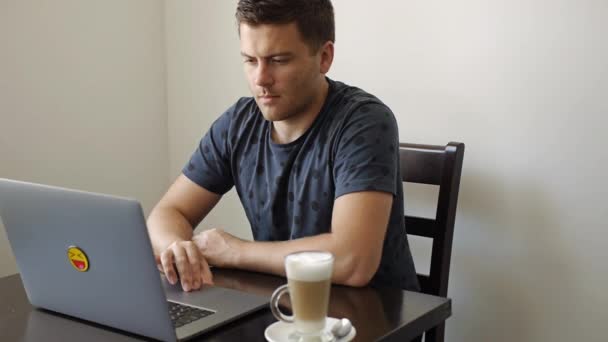 En mand arbejder på en bærbar computer i en cafe – Stock-video