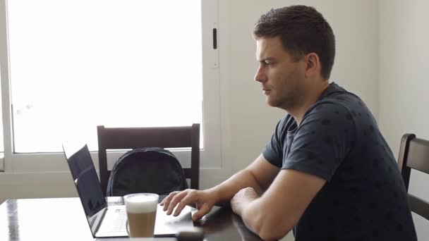 Un hombre trabaja en una laptop en un café — Vídeos de Stock