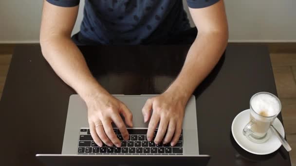 Un hombre trabaja en una laptop en un café — Vídeos de Stock