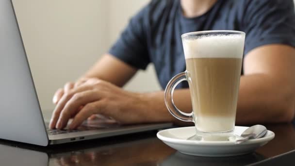 Un hombre trabaja en una laptop en un café — Vídeos de Stock