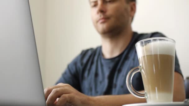 Een man werkt op een laptop in een café — Stockvideo
