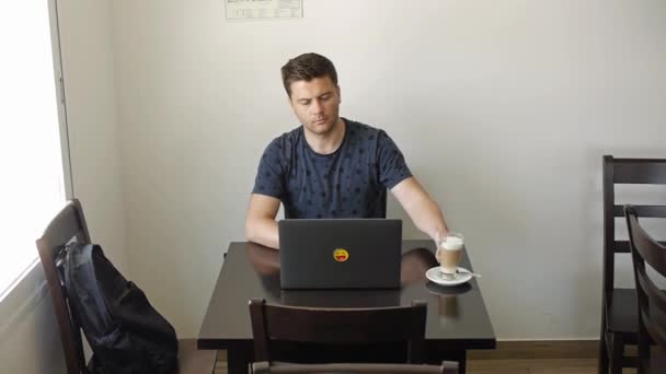 Een man werkt op een laptop in een café — Stockvideo