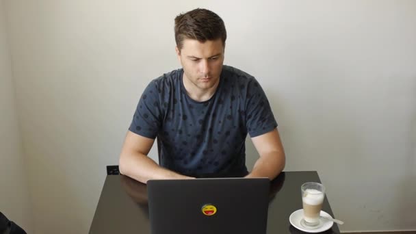 Egy férfi laptopon dolgozik egy kávézóban. — Stock videók