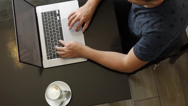 Un hombre trabaja en una laptop en un café — Vídeos de Stock