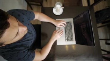 Bir adam kafede dizüstü bilgisayarda çalışıyor.