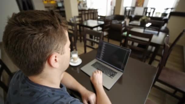 Un hombre trabaja en una laptop en un café — Vídeo de stock