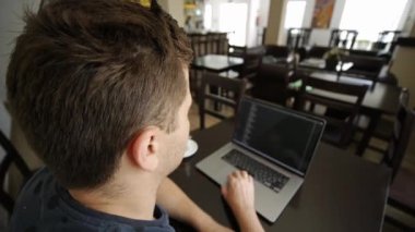 Bir adam kafede dizüstü bilgisayarda çalışıyor.