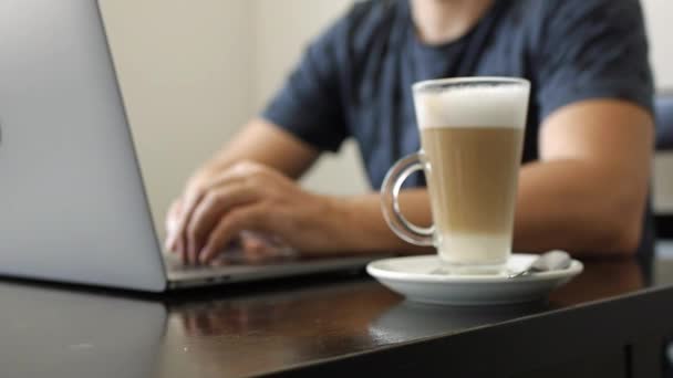 Ένας άντρας δουλεύει σε ένα λάπτοπ σε ένα καφέ. — Αρχείο Βίντεο