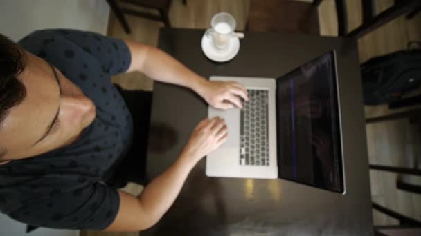Facet pracuje na laptopie w kawiarni. — Wideo stockowe