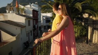 Hamile beyaz kadın ve erkek, yüksek gözlem güvertesindeki dağlara karşı kasabayı izliyorlar. Çiftler birlikte vakit geçiriyorlar..