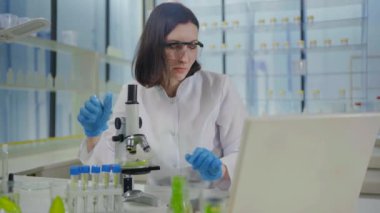 a Dissatisfied and puzzled, a female scientist looks through a microscope in a modern laboratory