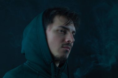 Siyah arka plandaki kapüşonlu genç adam. erkek portresi