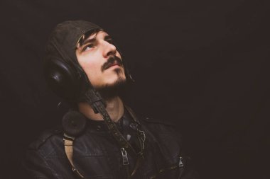 Eski tarz erkek portresi. Siyah arka planda eski model havacılık kıyafeti giyen genç adam.