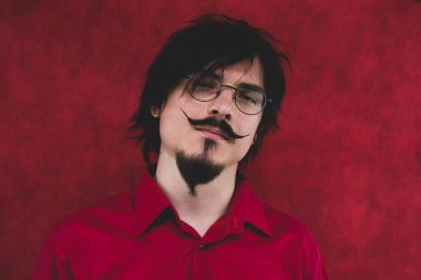 Kırmızı arka planda kırmızı gömlekli gözlüklü adam. erkek portresi