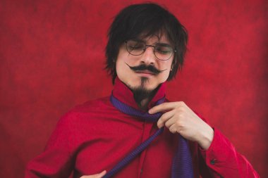 Genç adam kravatını çıkarıyor. Kırmızı arkaplanda anlamlı erkek portresi