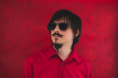 Kırmızı arka planda güneş gözlüklü genç adam. erkek portresi