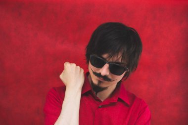 Kırmızı arka planda güneş gözlüklü genç adam. erkek portresi