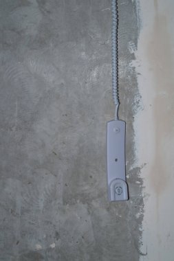 Gri beton arka planda dahili telefon alıcısı. Telefonun kabloda asılı. Kapatın.