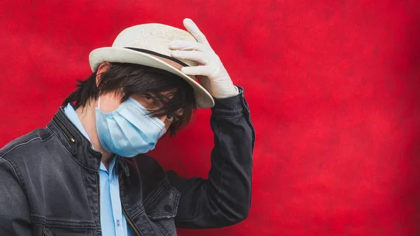 マスクと帽子をかぶった若い男 赤い背景の男性の肖像画です ウイルス対策 — ストック写真