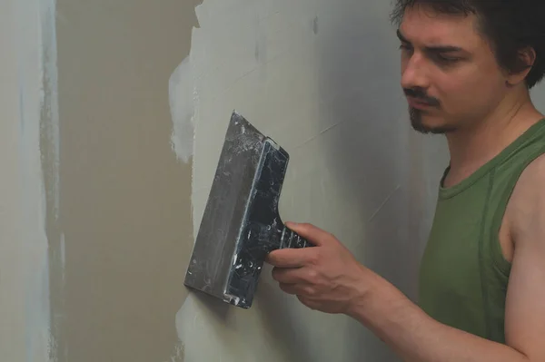 Man doing repairs. worker applies with construction putty to the wall. working process