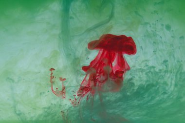 Suda boya var. Sıvı mürekkep. Soyut arkaplan. Sıvı içinde renkli sıçramalar. kırmızı ve yeşil renkler