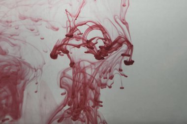 Suyun arka planında kırmızı mürekkep var. Sıvının içine boya sıçramış.