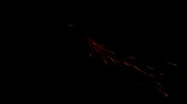 Adam çeliğin üzerinde dairesel testere ile çalışıyor. Siyah arkaplanda sıcak metalden kıvılcımlar uçuşuyor.