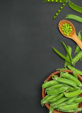 Kavanozlu taze bezelyeler ve siyah arka planda kaşık..