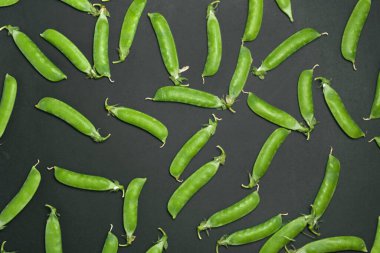 Siyah arka planda kabuklu taze bezelyeler..