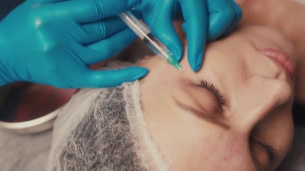 Beauty and injections concept. Experienced beautician entering subcutaneous prick with required active components into female face for tightening and lifting. — Stock Video
