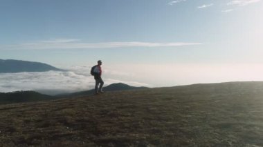 Sırt çantalı turist bulutların üzerinde yürüyor