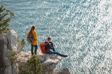 İki gezgin denize karşı büyük bir kayanın üzerinde dinleniyor.