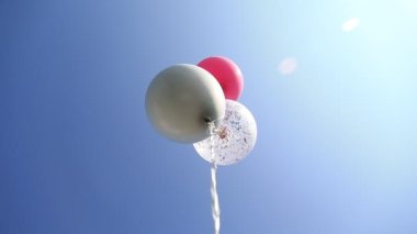Mavi gökyüzünde yüzen üç renkli helyum balonu. Doğum günü kutlaması.