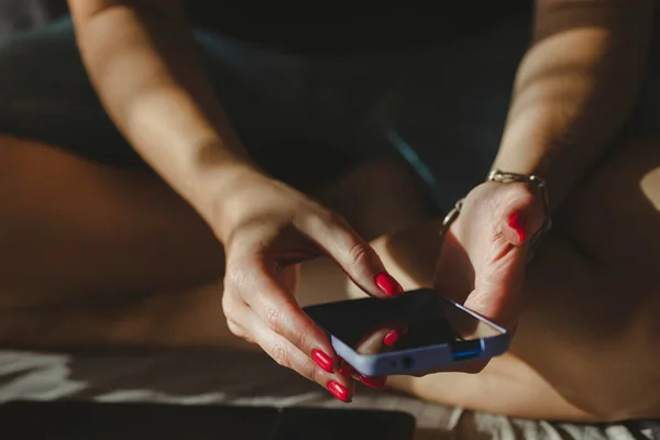 Cep telefonu kullanan bir kadın, ellerinde kırmızı oje manikürlü eller. İnternetten alışveriş.