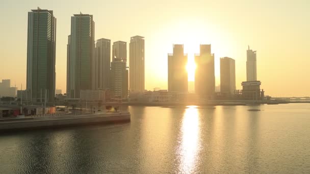 Nascer do sol na ilha Al Reem em Abu Dhabi, paisagem urbana. Silhuetas do edifício alto edifícios modernos com o sol que se levanta atrás deles. — Vídeo de Stock