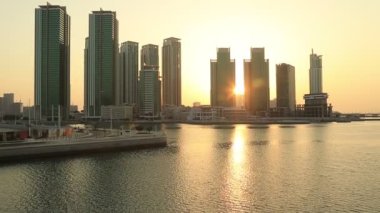 Abu Dabi 'deki Al Reem adasında gün doğumu, şehir manzarası. Güneş yükselen modern binaların siluetleri..