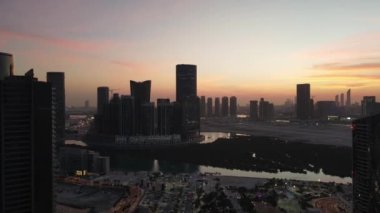 Abu Dabi 'de günbatımı, Al Reem adasındaki hava manzarası denizdeki mangrovlar arasında modern gökdelenlerle çevrili.