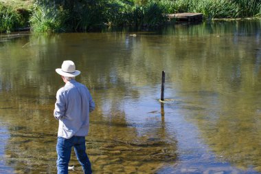 Emeklilik yaşında yaşlı bir erkek yazın bir derede dinlenir.