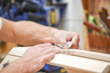 Adam mobilya yapımında zımpara kağıdı ile ahşabı zımparalıyor.