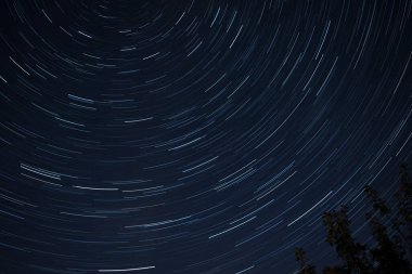 Açık bir gecede yıldız izleri gökyüzünde dairesel bir şekil oluşturur.