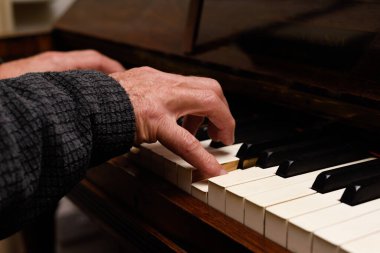 Olgun erkek eller piyano çalarken ellere ve klavyeye odaklanır.