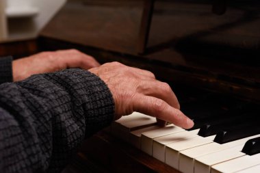 Olgun erkek eller piyano çalarken ellere ve klavyeye odaklanır.