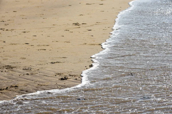 Sea shore with ocean water lapping at the sandy beach