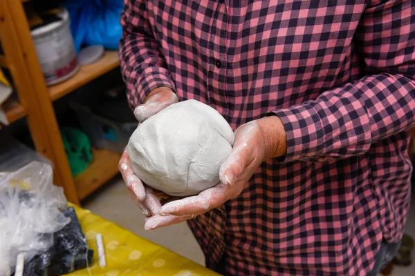 Female hands making ceramic art and pottery in a workshop class for mature people