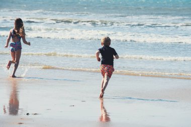 İki çocuk yaz tatilinde yüzmek için denize koşar.