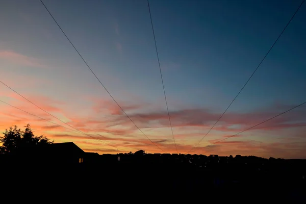 日落时分的天空上有住宅的电缆 — 图库照片