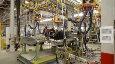 Otomobil fabrikası, araba üretim süreci. İşçiler araba parçalarını kaynaklıyor..