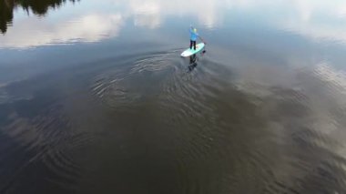 Orman gölünde sup-board kullanan bir kız