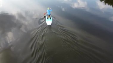 Orman gölünde sup-board kullanan bir kız
