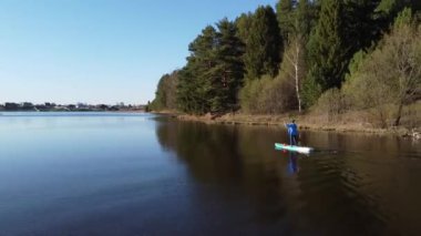 Orman gölünde sup-board kullanan bir kız